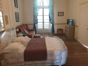 a bedroom with a bed and a chair and a window at Le Chateau in Châteauponsac