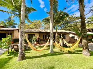 a hammock in front of a house with palm trees at Chalés do Holandês Eco Pousada in Bombinhas