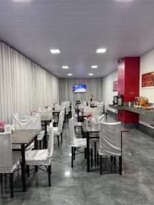 ein Esszimmer mit Tischen und weißen Stühlen in der Unterkunft Pluma Hotel Cidade in Americana