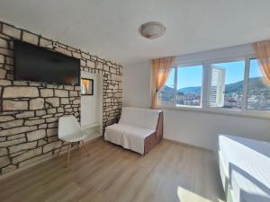 a room with a stone wall and a chair and a tv at House Zarko in Pučišća