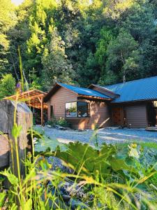 Cabaña de madera con techo azul en el bosque en Cabañas Alto del Bosque, en Coñaripe