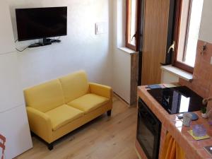 sala de estar con sofá amarillo y TV en Il Nido del Lago del Turano, en Castel di Tora