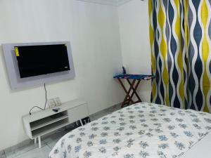 a bedroom with a bed and a tv on the wall at GodIsGood Residency in Yaoundé +13 photos