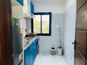 a small kitchen with blue cabinets and a window at GodIsGood Residency in Yaoundé
