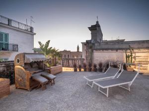 a patio with two lounge chairs and a building at Palazzo Alchimia in Fasano
