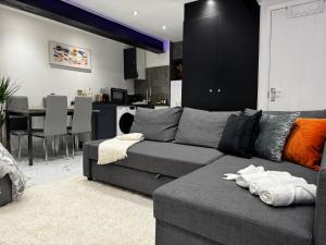a living room with a gray couch and a kitchen at Gorgeous Holiday Home 5 minutes from Central London in London