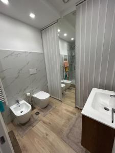 a bathroom with two sinks and a toilet and a mirror at BeB Loft Corigliano Rossano CS in Rossano Stazione