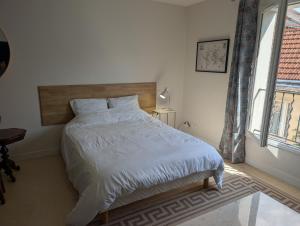 Schlafzimmer mit einem Bett mit einem Kopfteil aus Holz und einem Fenster in der Unterkunft Joli appartement cœur de ville in Poitiers + 2 Fotos