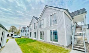 a row of houses with a car parked in front at Surfbude, Olpenitz - moderne Ferienwohnung in direkter Strandnähe mit eigenem Eingang, Sauna, Kaminofen, Balkonterrasse und Parkplatz in Kappeln
