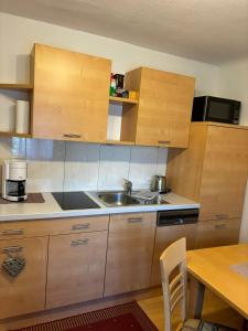 a kitchen with wooden cabinets and a sink and a table at Appartement Unterstein 1 in Niedernsill