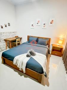 ein Schlafzimmer mit einem Bett mit einer blauen Decke und einem Tisch in der Unterkunft Cozy 1BR Uluwatu Room Pool in Uluwatu