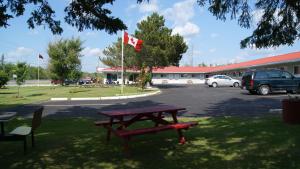 uma mesa de piquenique com uma bandeira canadiana num parque de estacionamento em Blue Jay Motel em Peterborough