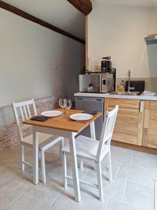 a kitchen with a table and two chairs and a counter at Gîte avec piscine couverte in Saint-Julien-de-Peyrolas