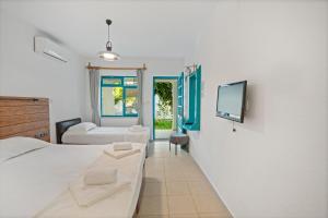 a bedroom with two beds and a tv on a wall at Avlu Otel Palamutbükü in Datca