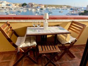 a table with two chairs and wine glasses on a balcony at Fronte mare Porto Vecchio in Lampedusa