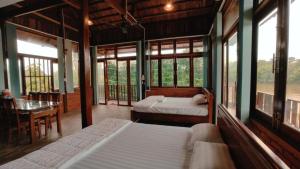 a bedroom with two beds and a table and windows at Coco Retreat in Tân Phú