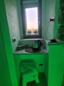 a green room with a window and a tea kettle at Suite Dolce Amore in Venosa +2 photos