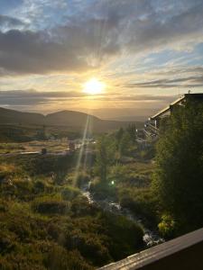 a view of a river with the sun setting in the distance at 6 Carn Dearg House in Aviemore