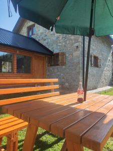 a picnic table with an umbrella and a bottle on it at Prenociste B&M - Lukomir in Lukomir