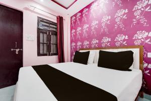 a bedroom with a white bed with a purple wall at HOTEL O PRIME STAR in Lucknow