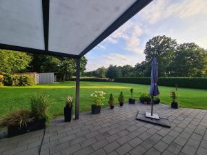 a patio with an umbrella and potted plants at Dat lütte Huus in Schneverdingen