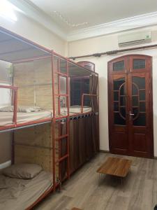 Cette chambre comprend 3 lits superposés et une porte en bois. dans l'établissement DA Travel Home - Hanoi Hostel, à Hanoï