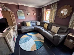 a living room with a leather couch and a rug at Pentre Country Studio in Wrexham