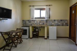 a small kitchen with a table and a refrigerator at Cais Dourado Pousada in Barra Grande