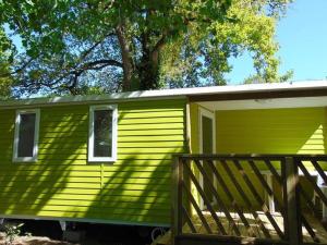 ein kleines grünes Haus mit einer Holzveranda in der Unterkunft Mobil-home pour 4 pers avec terrasse - API-1-52-739 in Avrillé