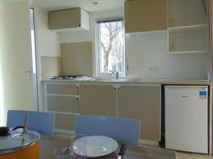 a kitchen with a table and chairs and a sink at Mobil-home pour 4 pers avec terrasse - API-1-52-739 in Avrillé +7 photos