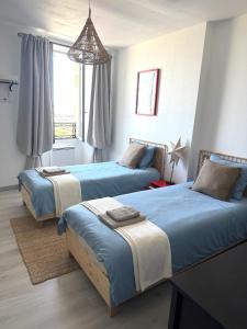 a bedroom with two beds and a window at La Belle Escale in Pauillac