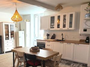 a kitchen with white cabinets and a table with chairs at La Belle Escale in Pauillac