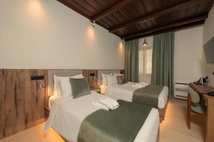 a hotel room with two beds and a desk at Balcon Makrinitsa in Makrinitsa