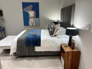 a bedroom with a bed and a table with a lamp at Topiary Lux Studio 16! in Herolds Bay