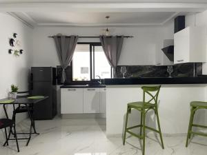 a kitchen with white cabinets and green bar stools at jasmin in El Aouina