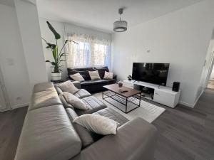 a living room with a couch and a flat screen tv at Séjour détente et confort au calme d une impasse in Garges-lès-Gonesse