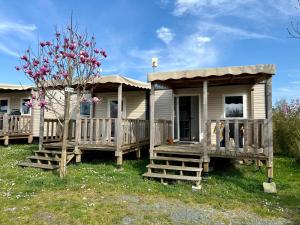 a house with a porch and a tree at Camping de la Loire in Cordemais
