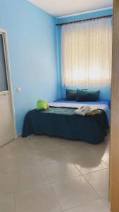a bedroom with two beds with blue walls and a window at Ela apartament in Golem