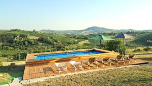 a pool with chairs and umbrellas on a hill at Residenza Menta CASA GUARNONE in Mornico Losana