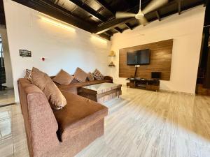 a living room with a couch and a flat screen tv at Zenstays Villa Igatpuri in Igatpuri