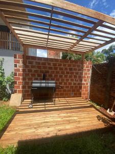 a barbecue grill on a wooden deck under a brick wall at Monoambiente en posadas 2 in Posadas