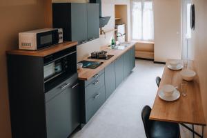 eine Küche mit blauen Schränken, einer Mikrowelle und einem Tisch in der Unterkunft La Maison MMM - Proche Centre & Commerces in Châteauroux + 22 Fotos
