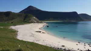a beach with a mountain in the background at Feriehus med flott havutsikt ved Hauklandstranden in Leknes