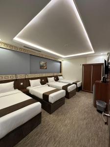 a hotel room with three beds and a tv at فندق برايت in Mecca