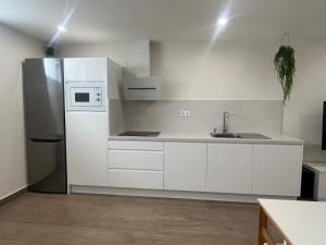 a kitchen with white cabinets and a stainless steel refrigerator at Loft Puerto Real in Puerto Real