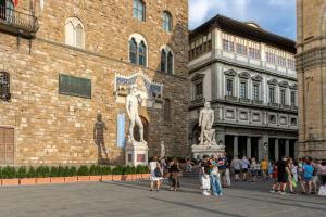 a group of people standing in front of a building with a statue at Signoria Vista by Halldis in Florence