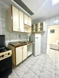 a kitchen with white cabinets and a white refrigerator at A 1 Minuto da praia in Santos