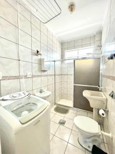 a white bathroom with a toilet and a sink at A 1 Minuto da praia in Santos