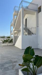 a white building with stairs and a potted plant at Casa Vacanza Marijò in Sant'Isidoro