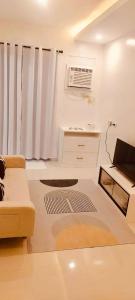 ein weißes Wohnzimmer mit einem Sofa und einem Fenster in der Unterkunft Svens Place in Puerto Princesa